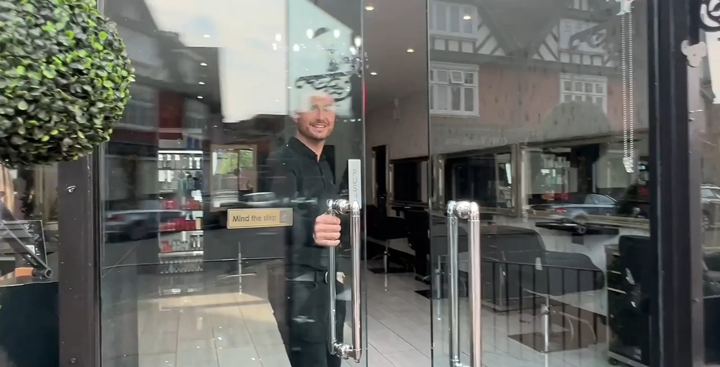 Lewis opening the glass door of Garretts Hair Boutique on Church Street, Weybridge